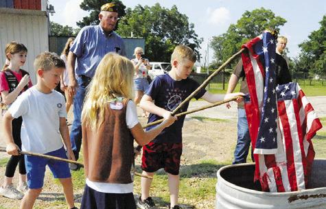 AREA CHILDREN UNDER THE supervision of members of VFW Post 4458 retired these flags by burning on Flag Day, June 14, during a ceremony at the post. -- Tribune photo by Denise Squier